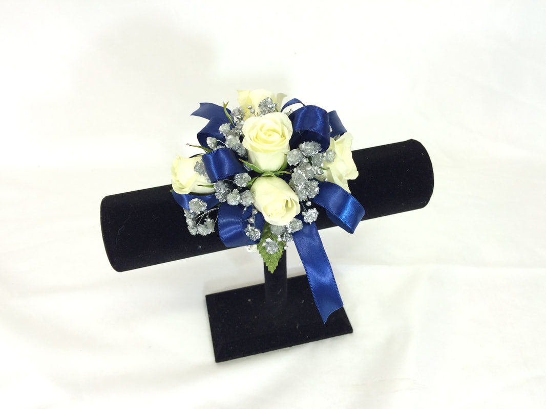 White rose wristlet with silver babies breath and dark blue bow